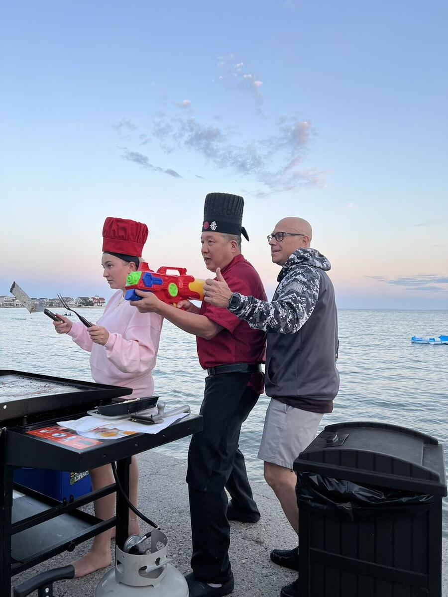 Happy Hibachi chefs entertaining a guest at a Connecticut waterfront party